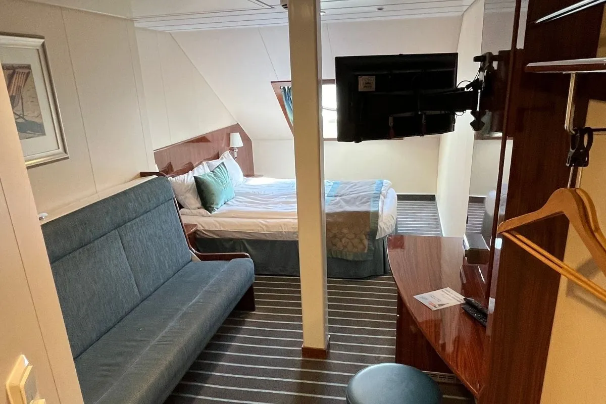 A cabin on MS Bergensfjord with a double bed, a sofa bed, a desk and a TV