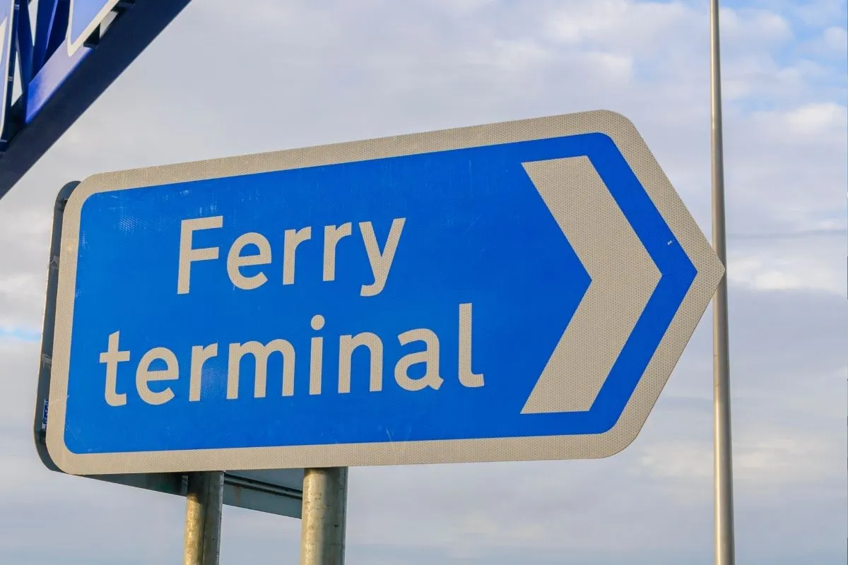 A blue road sign reading Ferry terminal with an arrow
