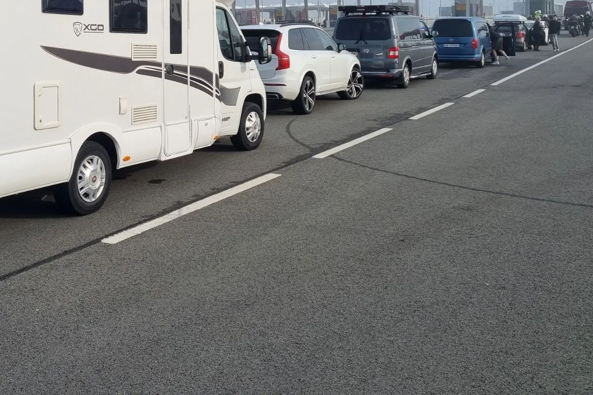 A motorhome and cars queued close together waiting to board